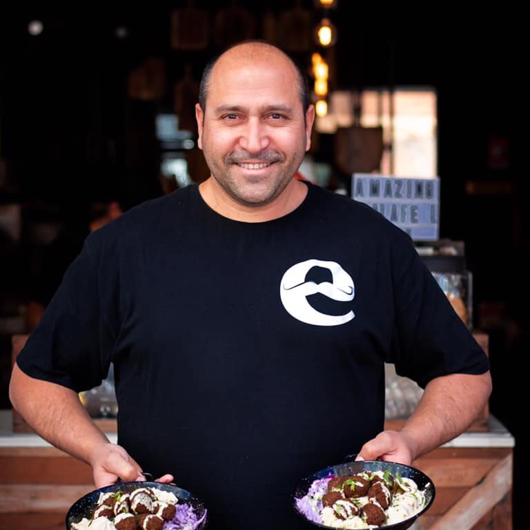 Issi, founder of Chapter E, holding two plates of food