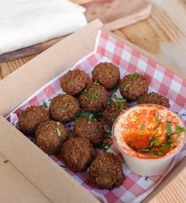 Box of falafel balls with a small dip