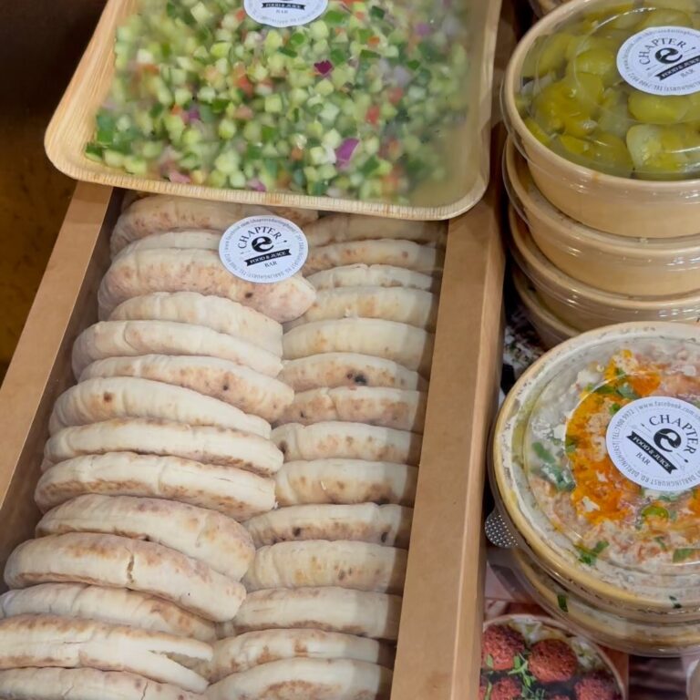 Stacked pita and tubs of hummus packed for a catering delivery