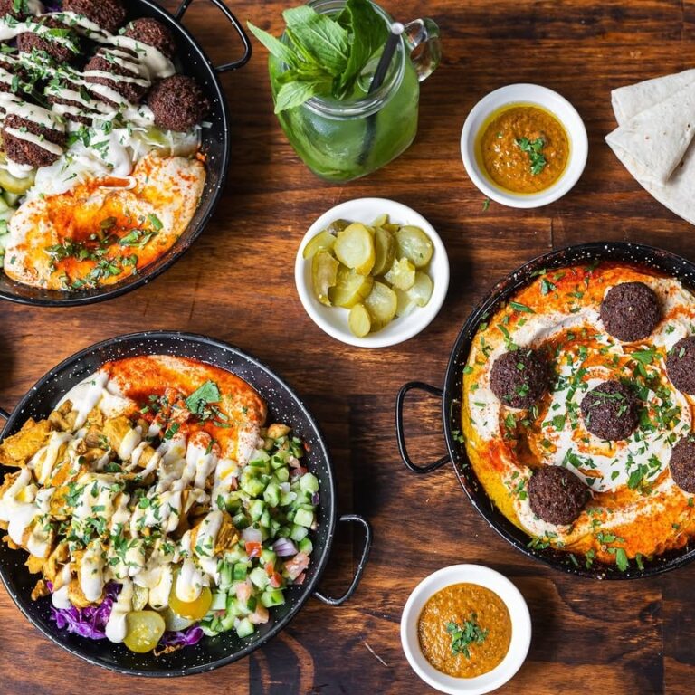 Hummus bowls, chopped salad and drinks on a wooden table